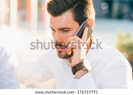 Half length of young handsome black hair caucasian modern businessman talking smartphone in city backlight- business, working, communication concept