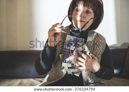 Senior woman watching old photos. Sadness