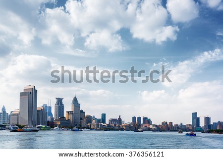View of the Bund, Shanghai, China. Waterfront of the Huangpu River is popular tourist destination. Self-propelled barges and boats on the river. Shanghai is transport hub with busiest container port.