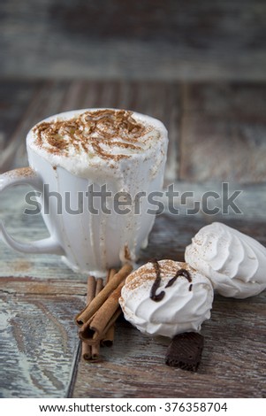 Hot coffee with marshmallows in a cup on the wooden background