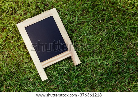 Chalk board on grass field with sunlight background