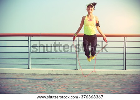 young fitness woman jumping rope at seaside Royalty-Free Stock Photo #376368367