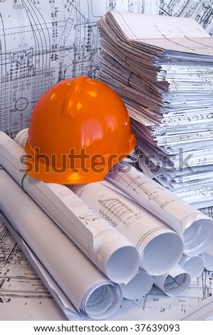 Orange helmet and heap of project and design drawings