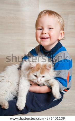 Cute toddler Kid baby boy playing with pet cat on the floor at home