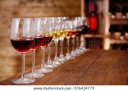 Many glasses of different wine in a row on bar counter Royalty-Free Stock Photo #376424779