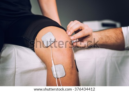 TENS electrodes positioned for knee pain treatment in physical therapy Royalty-Free Stock Photo #376434412