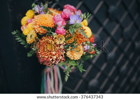 Wedding. The bride's bouquet. A bouquet of yellow, red and green with a white silk ribbon stands near a black forged gates