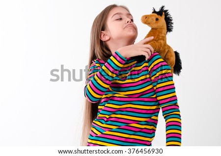 girl and a horse toy. beautiful girl with long hair plays a toy horse