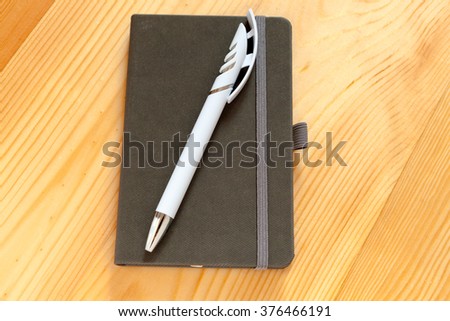 Notebook with pen on wood background