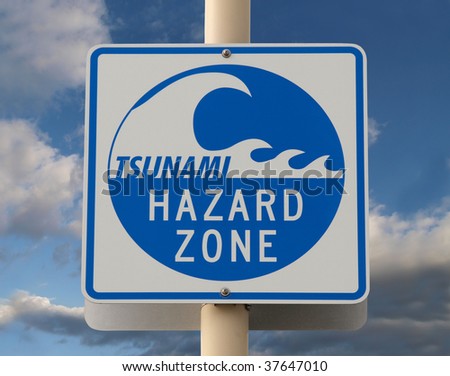 Tsunami warning sign with a cloud filled sky.