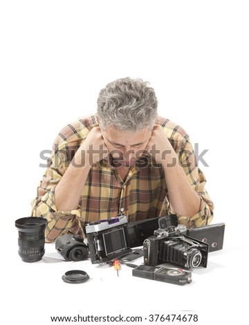 Male repairing an old camera at his workplace on white background