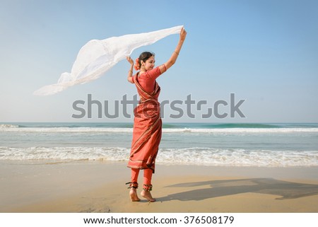 Indian woman feel freedom and standing near the beach in traditional saree clothing with white tissue in the hands