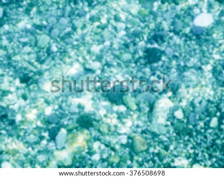 Defocused background of underwater pebbles at the seaside. Intentionally blurred post production for bokeh effect