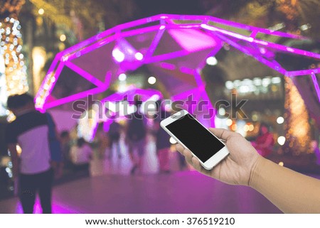 Man hand hold mobile phone, Front shopping mall, Light blurred outside.