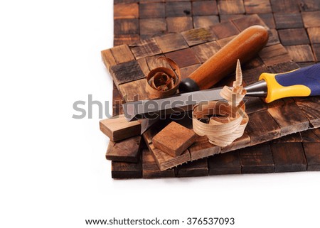 Mosaic tiles made of hard wood, two chisels, a shaving on a white background