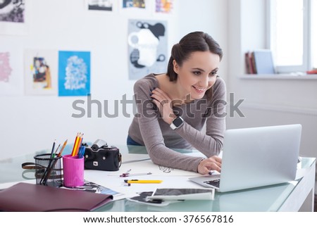 Attractive young photo artist is using a laptop