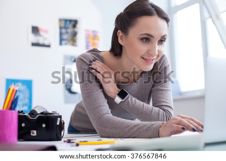 Cheerful female photographer is working with a computer