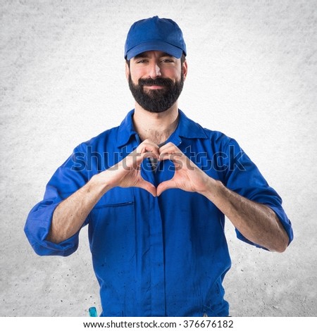 Plumber making a heart with his hands over textured background