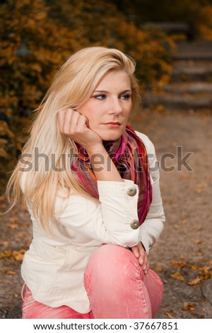 Picture of a young upset blond girl having an autumn depression in an autumn park
