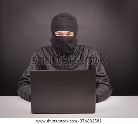 Laptop computer hacker - Male thief stealing data from laptop computer on black background