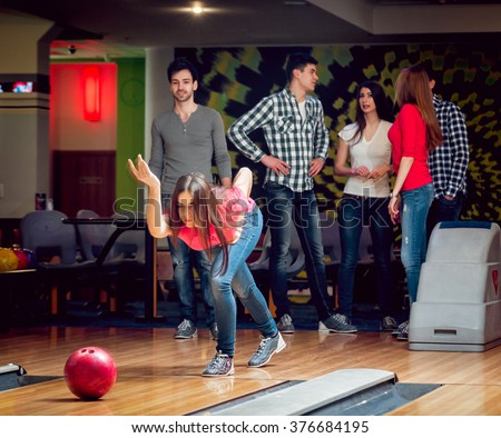 Happy guys and girl in bowling alley