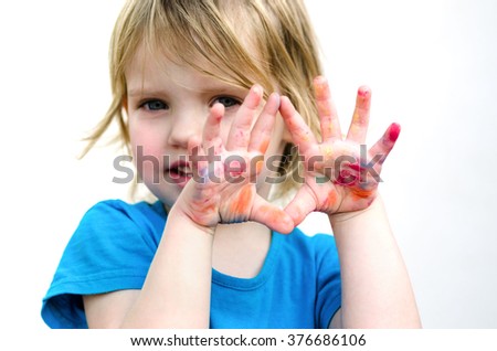 Cute preschooler girl with smile showing colored hands. Selective focus on palms.