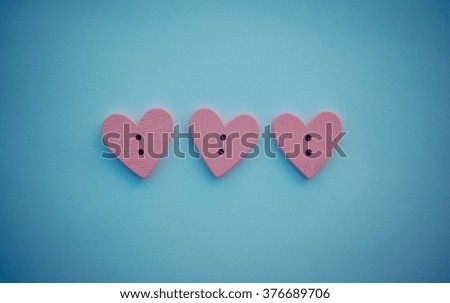 Lot of pink wooden buttons in the shape of a heart on a delicate retro blue color