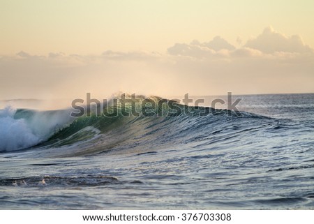 Ocean breaking surfing wave. Pipeline in evening sunset light. Beautiful tropical oceanic background postcard. Big water splashes on seascapes.