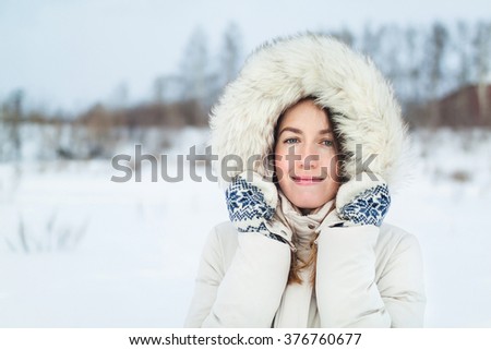 Christmas girl outdoor portrait. Woman in winter clothes on a snow field.