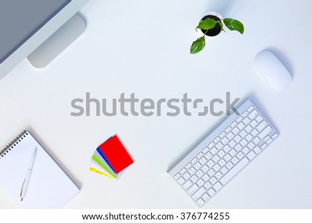 Modern trendy Working Place of Designer with large Computer Monitor Keyboard Notepad Pen and Mouse on White Desk with green Flower and collection of colorful Business Cards 