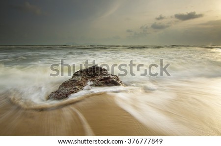 Beautiful landscape sunrise in the sea with stones on a long exposure.