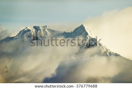 Snowy Mountain Peaks surrounded by clouds in the sunrise! Taken near Squamish, British Columbia, Canada.