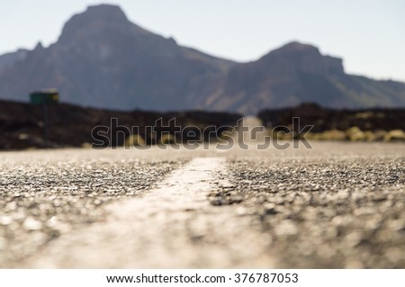 Empty desert road with mountains on background, shallow depth of field