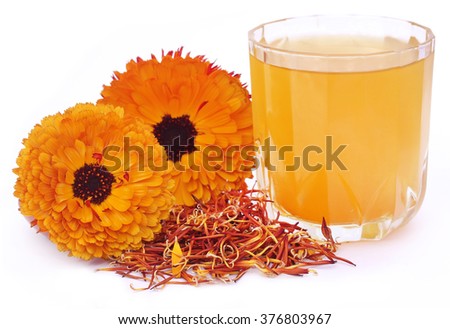 Herbal calendula flower with extract in a glass over white background