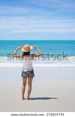 Back view of Travel asia woman with hat looking out of sea on a beach in summer, Koh Samet, Thailand