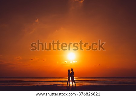 cute young beautiful couple posing on the beach at sunset, love each other, hipster style, happily smiling in sunglasses on a tropical island,outdoor portrait, closee up fashion, silhouettes, dawn