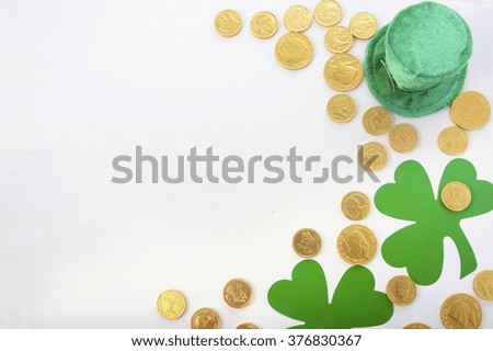 St Patricks Day Flat Lay including leprechaun hat, chocolate gold covered coins and shamrocks on white wood background, with copy space. 
