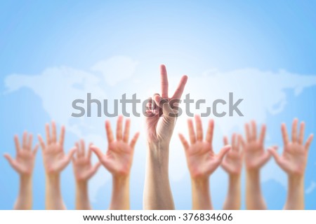 Leader's two fingers victory sign among blur hands crowd group for World participation, leadership, volunteer concept

