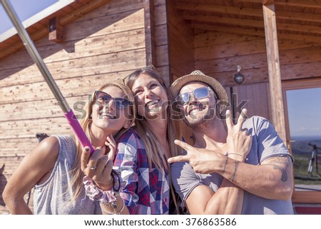 group of smiling friends taking funny selfie with smart phone on a vintage warm color filtered look