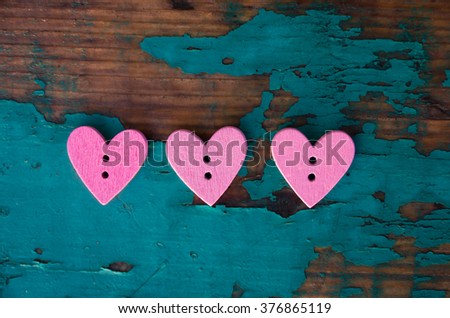 Beautiful soft pink buttons in the shape of a heart love wood on wood background with old green paint, vintage background of wood, old paint, wooden buttons, pink, top view