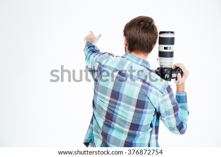 Back view portrait of a male photographer holding photo camera and pointing on something isolated on a white background