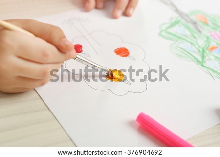 Child drawing tree with bright paints on paper, closeup