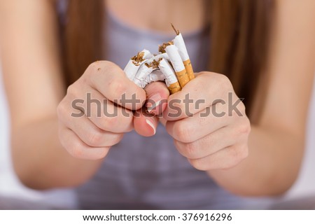 Quit Smoking, woman hands breaking bunch of cigarette. Royalty-Free Stock Photo #376916296