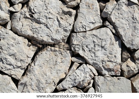 Outdoor of gray stone wall facade exterior of rocks of various sizes and forms on natural mural background, horizontal picture