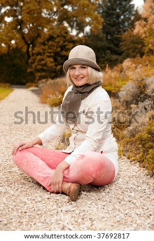 Picture of a young happy woman relaxing in an autumn park