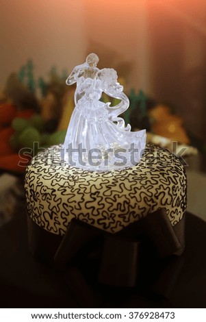 Sweet delicious big wedding chocolate cake sweet dessert decorated with adorable white ice figure of dancing groom and bride beautiful brown bow closeup indoor on blur background, vertical