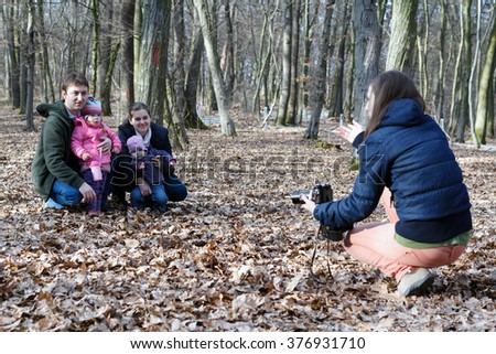 Young photographer women is taking pictures of a family with a couple of kids in the middle of the nature