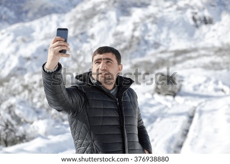 a young man walking on a winter day outdoors. Young man taking selfie  enjoying at the snow at winter day. 