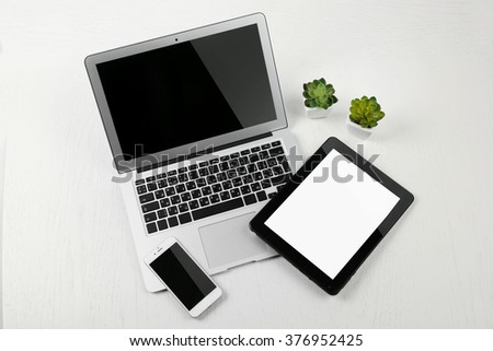 Different modern devices with green plants on light table