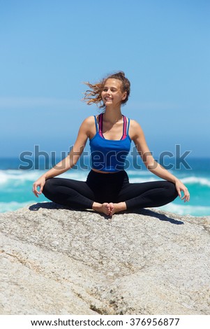 Young smiling yoga woman by the sea